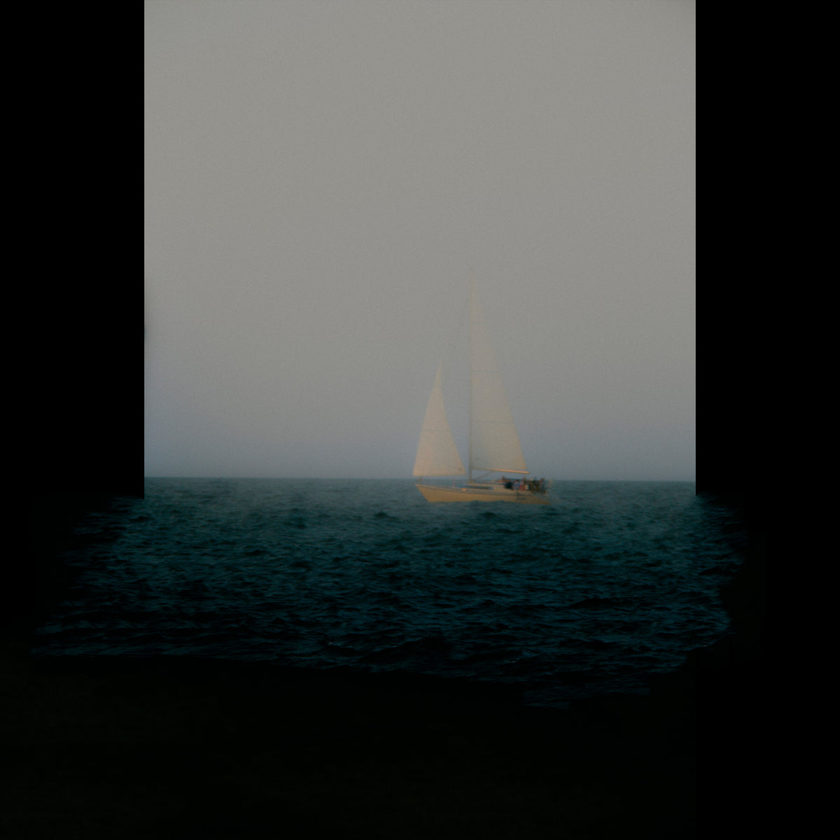 A small sailboat with white sails floats on dark blue water under a pale gray sky, framed by thick black vertical bars on the left and right.