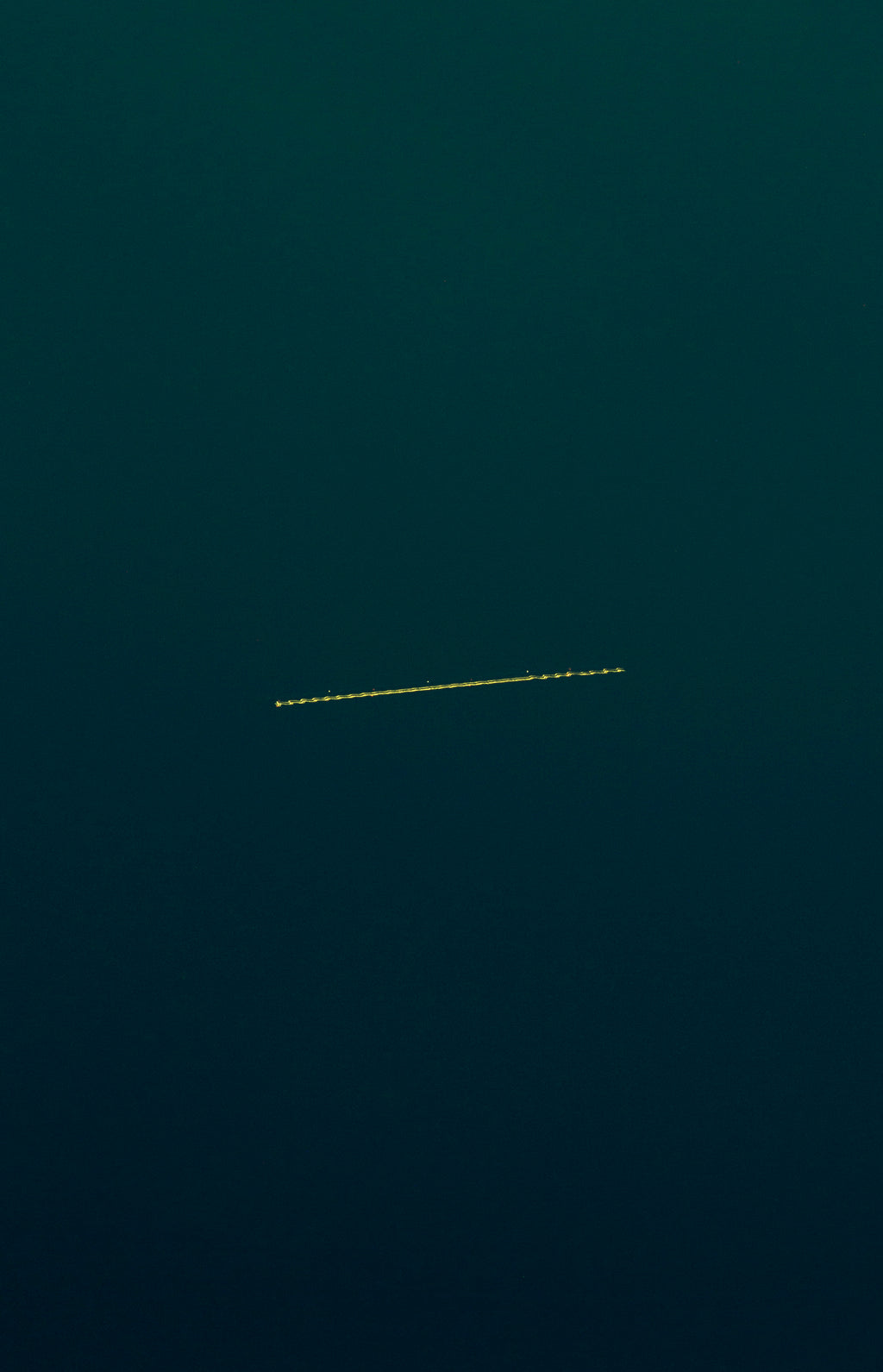 A dark teal sky with a thin horizontal yellow dotted airplane motion trail running across the center.