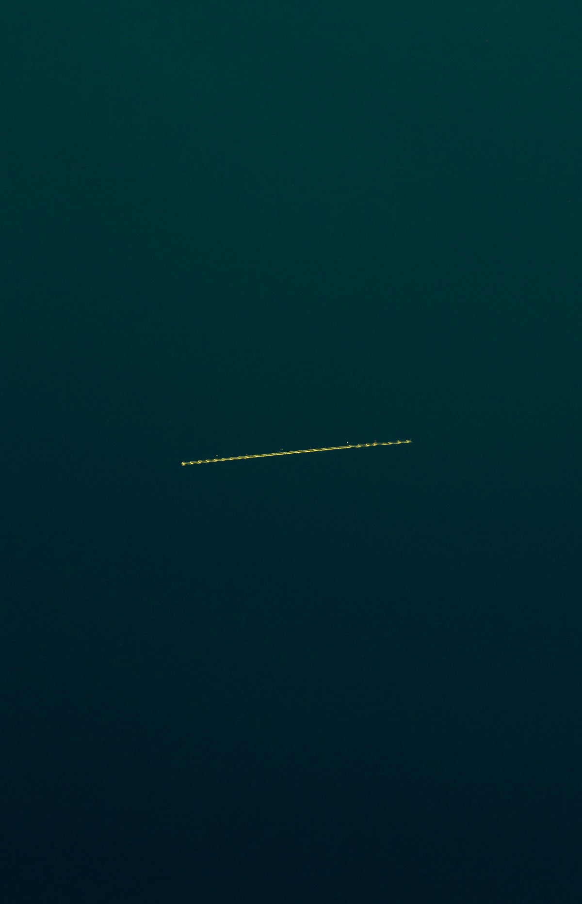 A dark teal sky with a thin horizontal yellow dotted airplane motion trail running across the center.