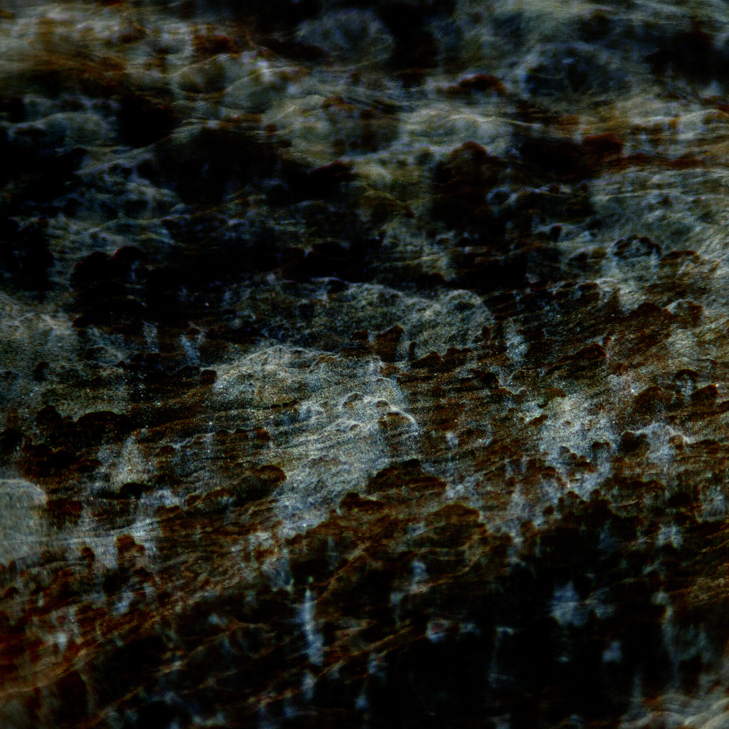 A close-up of a dark, marbled texture with black, deep brown, and gray tones, resembling polished stone or a highly textured surface.