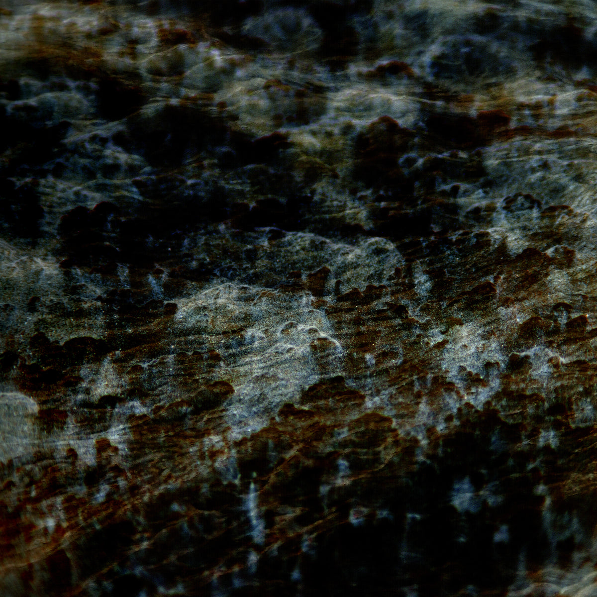 A close-up of a dark, marbled texture with black, deep brown, and gray tones, resembling polished stone or a highly textured surface.